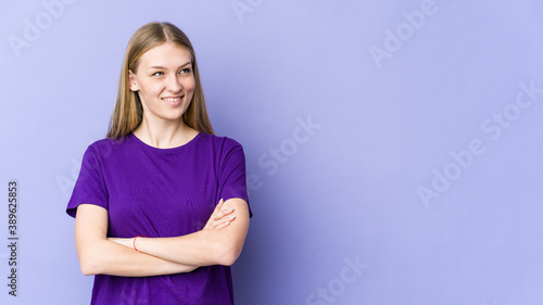 Young blonde woman isolated on purple background smiling confident with crossed arms.
