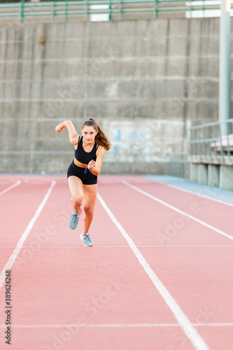 Smiling fit female teenager runner training on running track