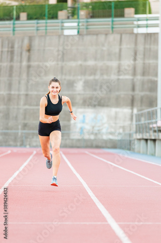 Smiling fit female teenager athlete training on running track