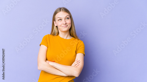 Young blonde woman isolated on purple background tired of a repetitive task.