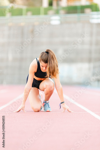 Confident female teenager athlete ready to run on running track