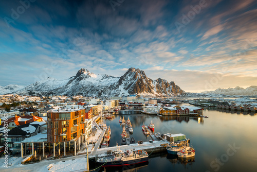 View over the port of Svolvaer on the Lofoten islands in colorful early morning sunrise in winter with snow