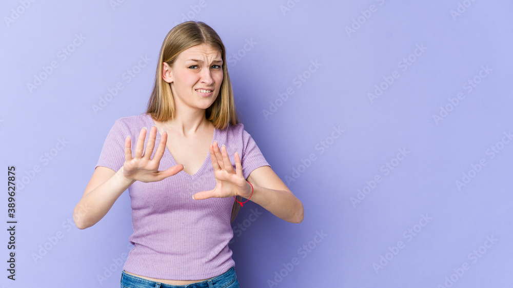 Young blonde woman isolated on purple background rejecting someone showing a gesture of disgust. Young blonde woman isolated on purple background rejecting someone showing a gesture of disgust.