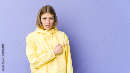 Young blonde woman isolated on purple background pointing to the side © Asier