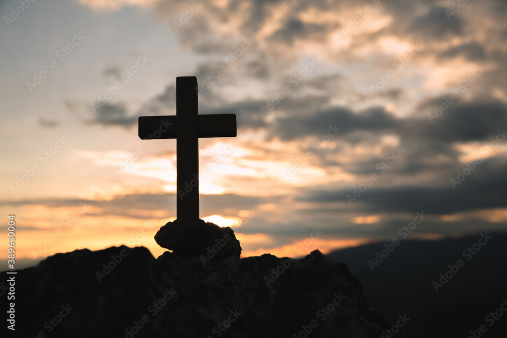 Silhouette of a cross on the mountain at sunset, hope concept.