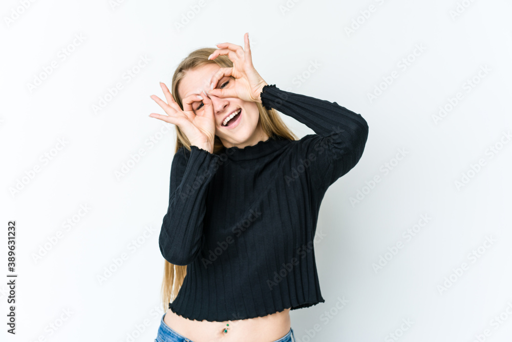 Young blonde woman isolated on white background showing okay sign over eyes Young blonde woman isolated on white background showing okay sign over eyes