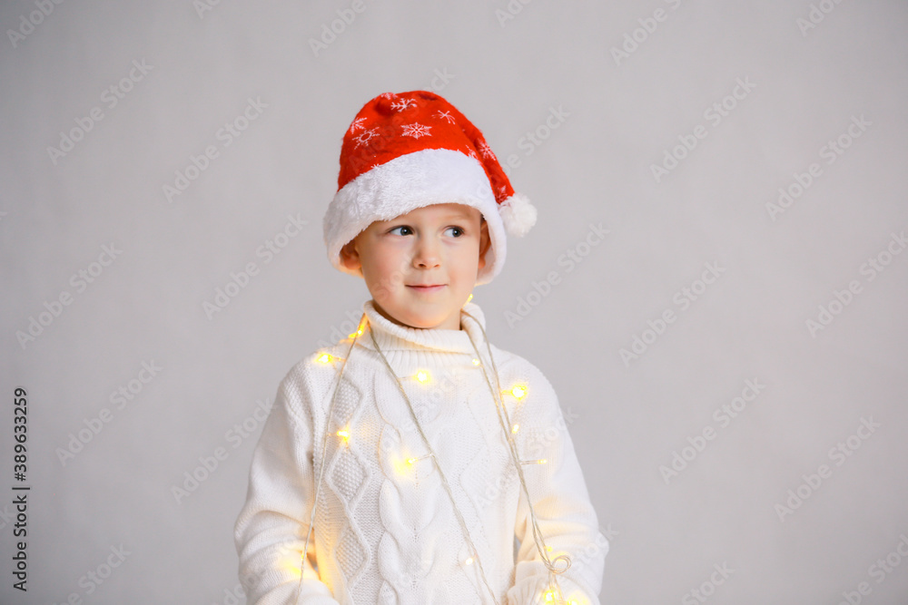 Happy child in Santa red hat. White isolated background. Christmas. Garland Happy child in Santa red hat. White isolated background. Christmas. Garland