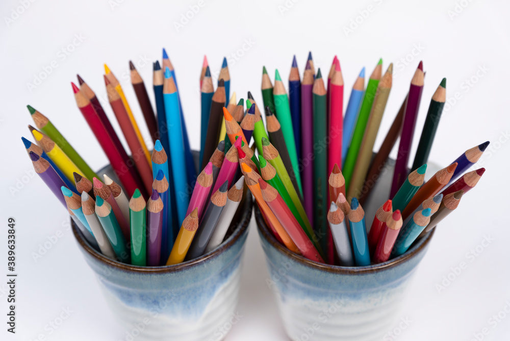 Fototapeta premium Colorful wooden crayons in mug for drawing and writing on white backgroud. Creativity collection in rainbow color for school and office.