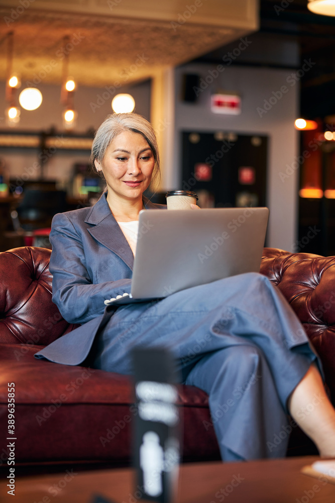 Beautiful woman sitting on sofa and working on laptop Beautiful woman sitting on sofa and working on laptop