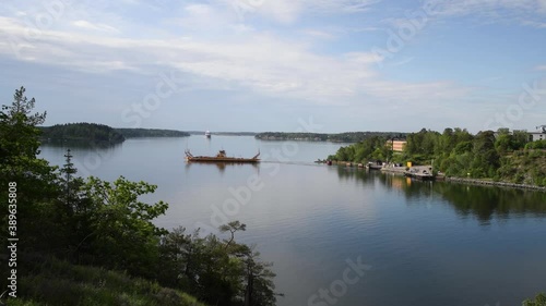 Car ferry passing the narrow passage Oxdjupet before the cruising ship from Stockholm to Finland pass by a sunny summer morning in the archipelago of Stockholm photo