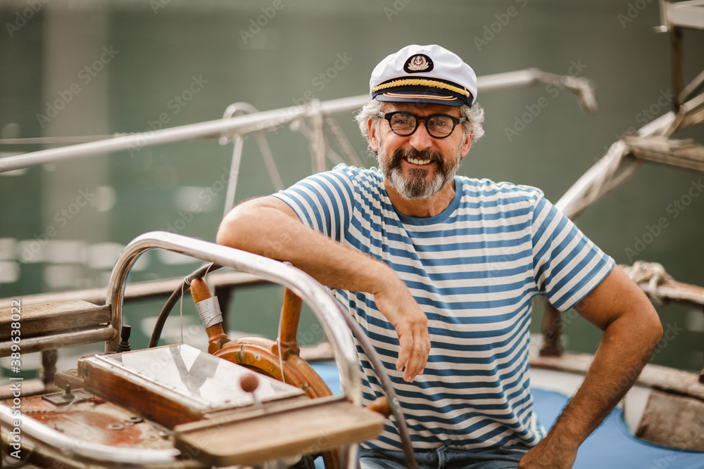 Mature man standing at helm of sailboat out at sea on a sunny afternoon. Mature man standing at helm of sailboat out at sea on a sunny afternoon.
