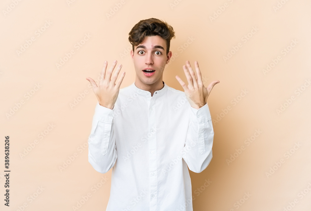 Young caucasian man isolated on beige background showing number ten with hands. Young caucasian man isolated on beige background showing number ten with hands.