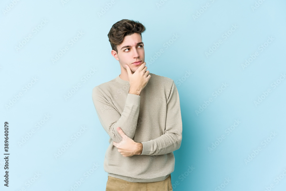 Young caucasian man isolated on blue background looking sideways with doubtful and skeptical expression. Young caucasian man isolated on blue background looking sideways with doubtful and skeptical expression.