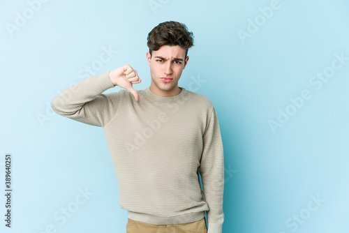 Young caucasian man isolated on blue background showing thumb down, disappointment concept.