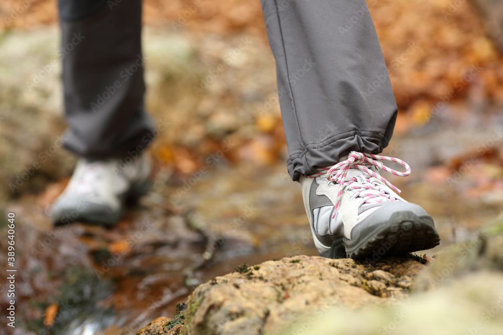 Trekker legs with boots crossing a river in autumn Trekker legs with boots crossing a river in autumn