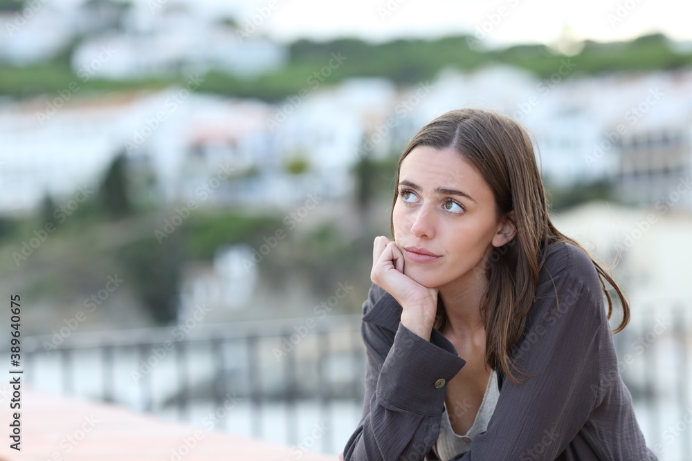 Worried woman thinking looking at side in a town