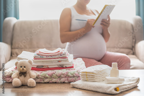 Pregnant woman is getting ready for the maternity hospital, packing baby stuff.