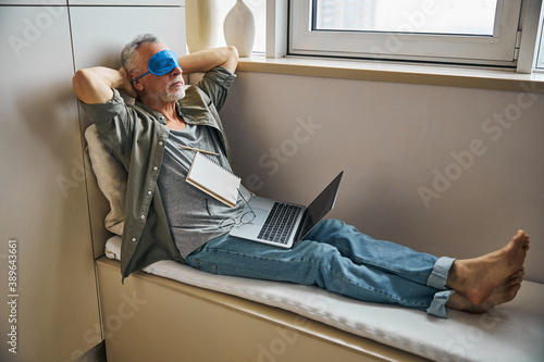 Elderly man giving eyes a break from working on laptop photo