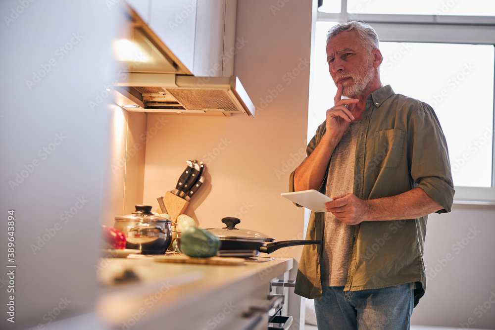 Elderly man at home considering ordering food delivery online