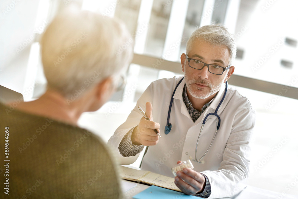 Fototapeta premium Mature practitioner in office listening to patient