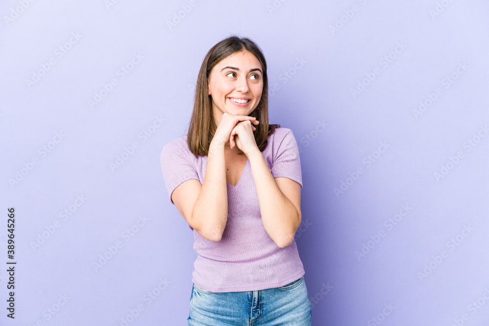 Young caucasian woman keeps hands under chin, is looking happily aside. Young caucasian woman keeps hands under chin, is looking happily aside.