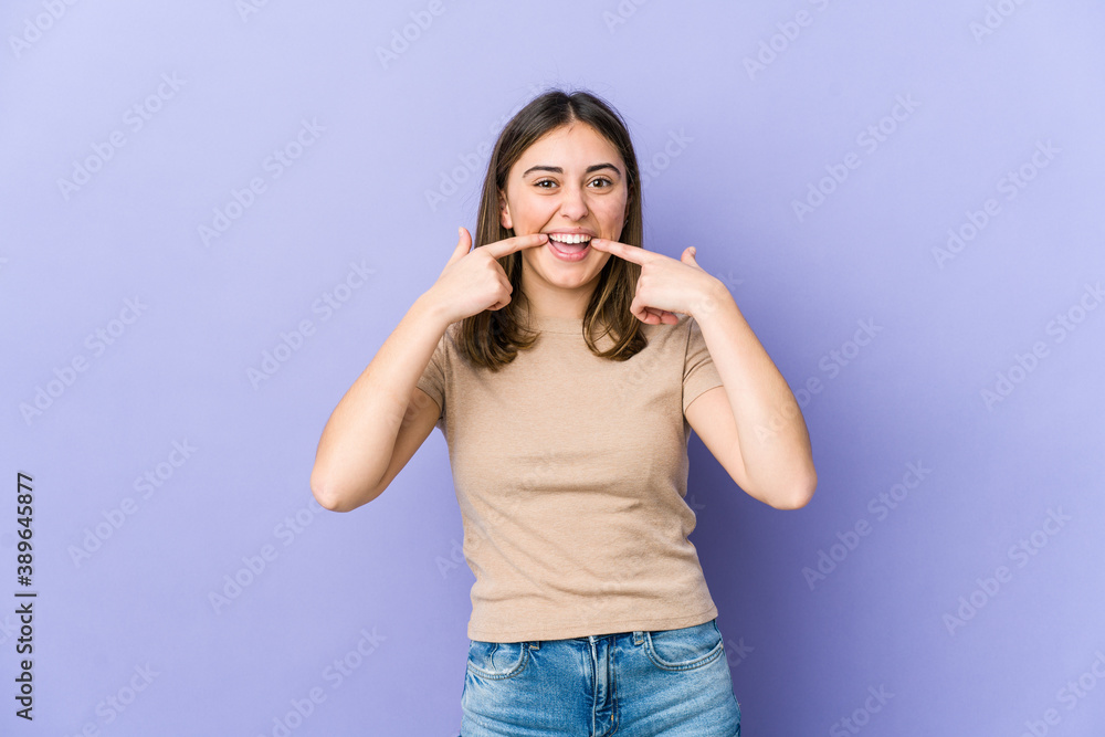 Young caucasian woman smiles, pointing fingers at mouth. Young caucasian woman smiles, pointing fingers at mouth.