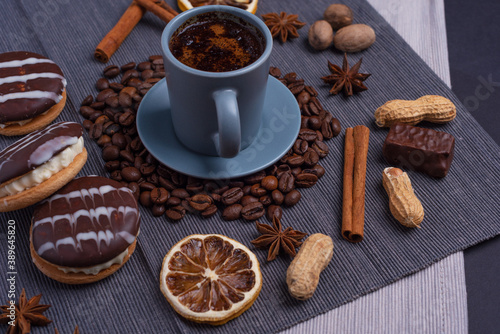 A cup of espresso is decorated with anise stars, cinnamon, sweets, dried lemons, acorns, peanuts in a beautiful dish.