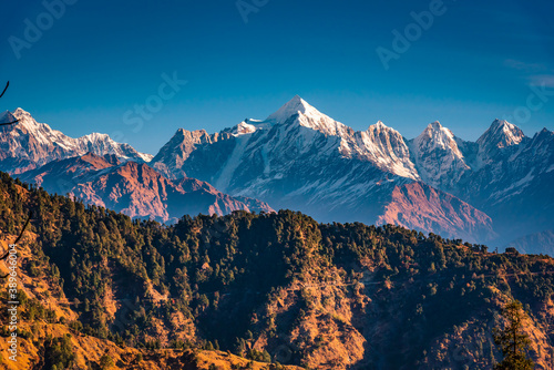 View of Snow cladded Panchchuli peaks falls in great Himalayan mountain range  & alpine grass meadows enroute to Khalia Top trekk trail at small hamlet Munsiyari, Kumaon region, Uttarakhand, India. photo