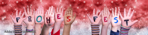Children Hands Building Colorful German Word Frohes Fest Means Merry Christmas. Red Snowy Christmas Winter Background With Snowflakes And Sparkling Lights