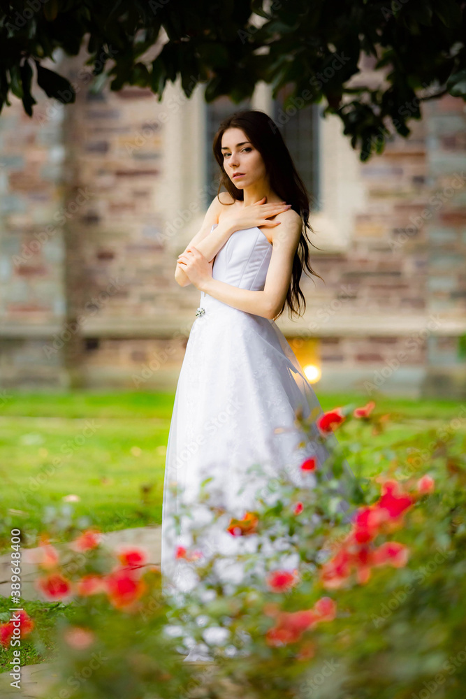 Beautiful girl wearing white wedding dress posing alone in the park