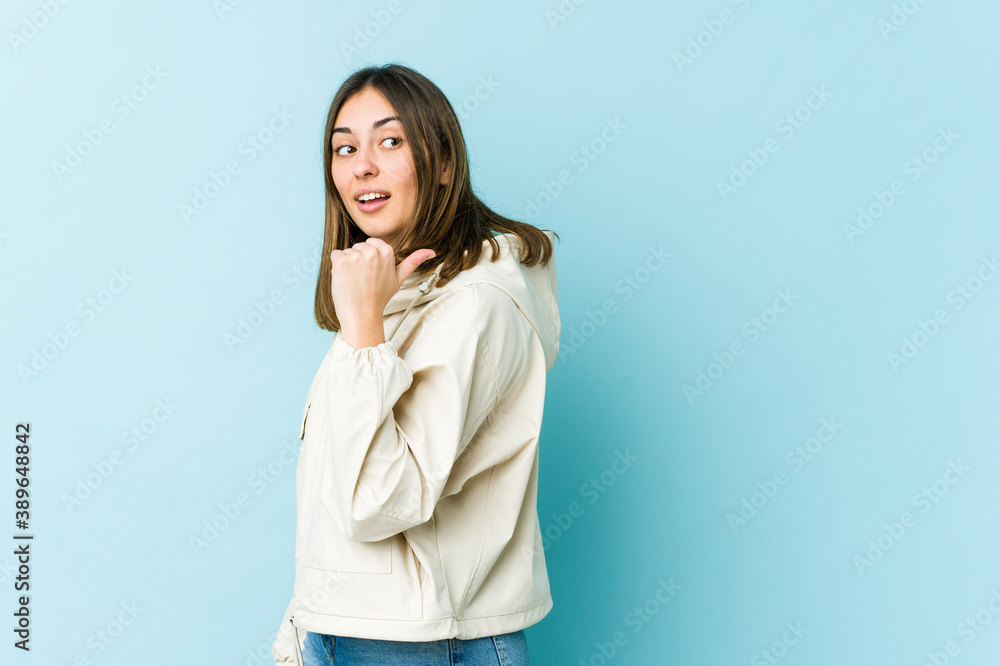 Young caucasian woman points with thumb finger away, laughing and carefree. Young caucasian woman points with thumb finger away, laughing and carefree.