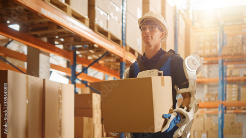 High-Tech Futuristic Warehouse: Worker Wearing Advanced Full Body Powered Exoskeleton, Walks with Heavy Cardboard Box. Delivery Exosuit amplifies Human strength. Portrait Shot