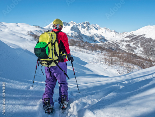 Active man ski touring on splitboard in mountains at snowy winter day