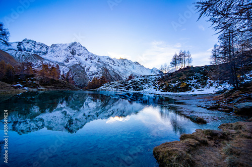 Reflections of snow capped mountains in a blue icy lake in the mountains