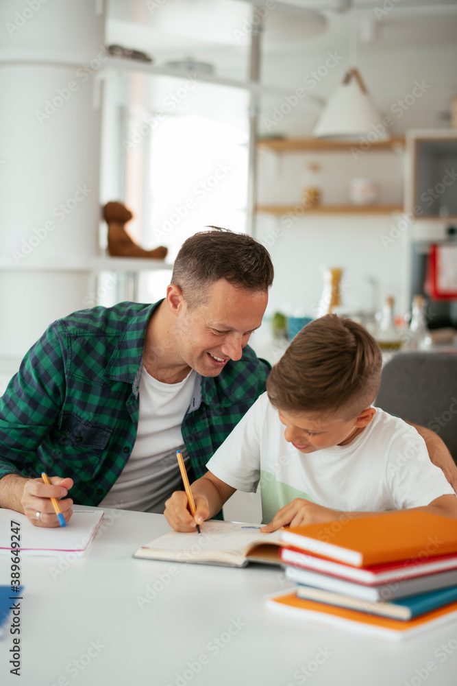 Father helping his son with homework at home. Little boy learning at home.. Father helping his son with homework at home. Little boy learning at home..