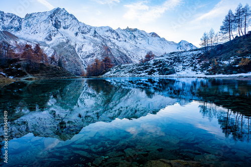 Fototapeta Naklejka Na Ścianę i Meble -  Reflections of snow capped mountains in a blue icy lake in the mountains