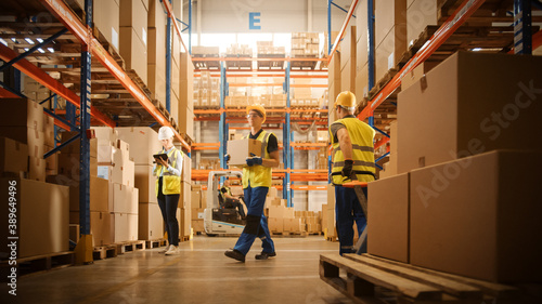 Retail Warehouse full of Shelves with Goods in Cardboard Boxes, Workers Scan and Sort Packages, Move Inventory with Pallet Trucks and Forklifts. Product Distribution Logistics Center. photo