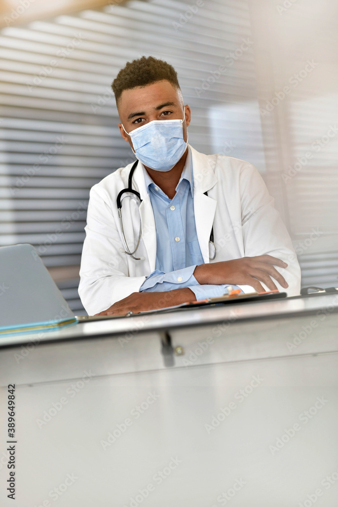 Young doctor working on laptop with face mask Young doctor working on laptop with face mask