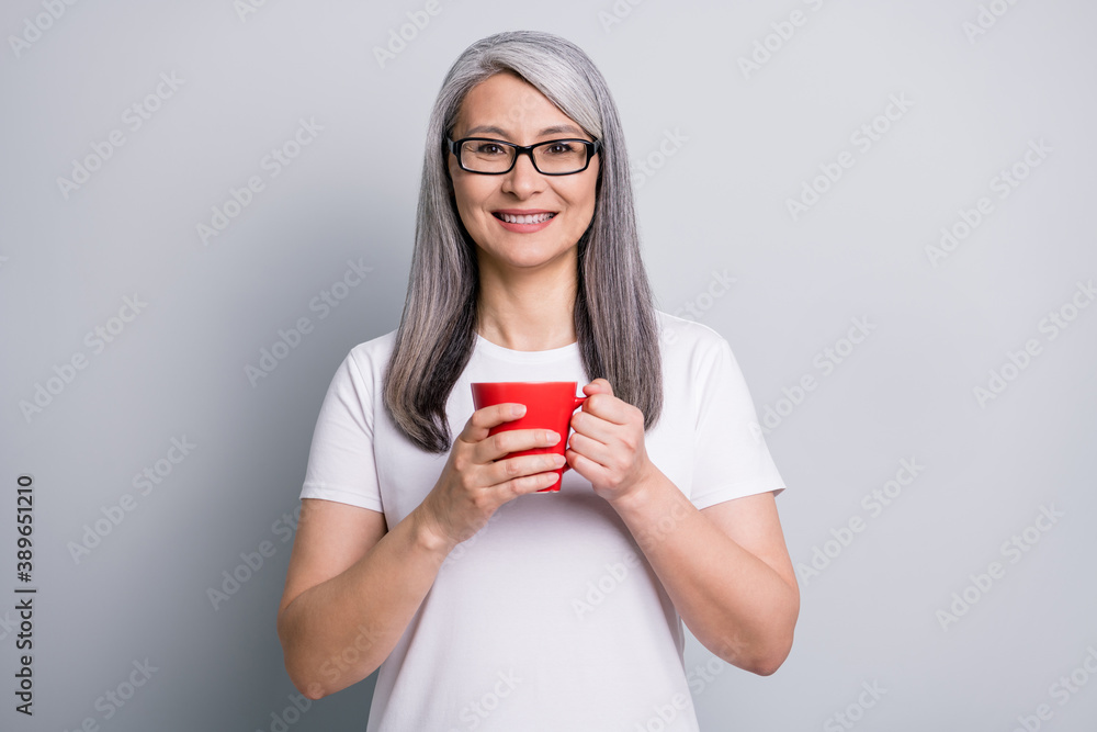 Photo of cute sweet senior lady wear casual outfit eyeglasses holding cup of tea hands arms isolated grey color background