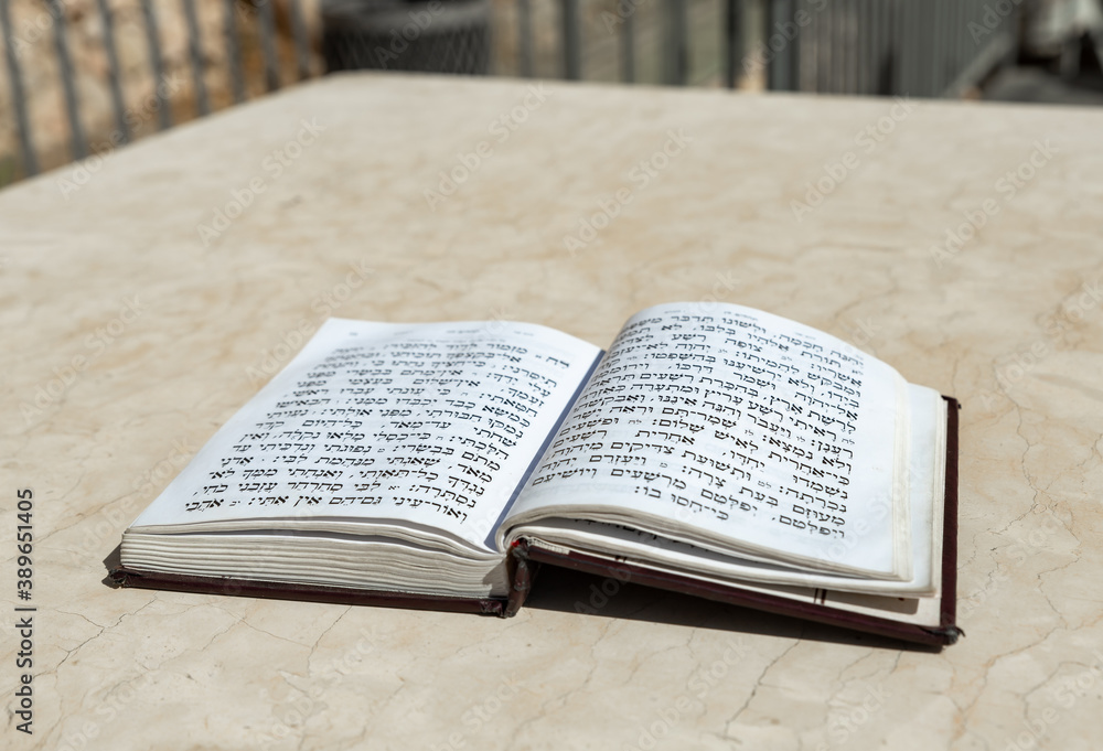 Fototapeta premium The open holy book of Jews with the text of prayers in Hebrew - Tehelim, lies on a table near the Western Wall in the old city. of Jerusalem in Israel