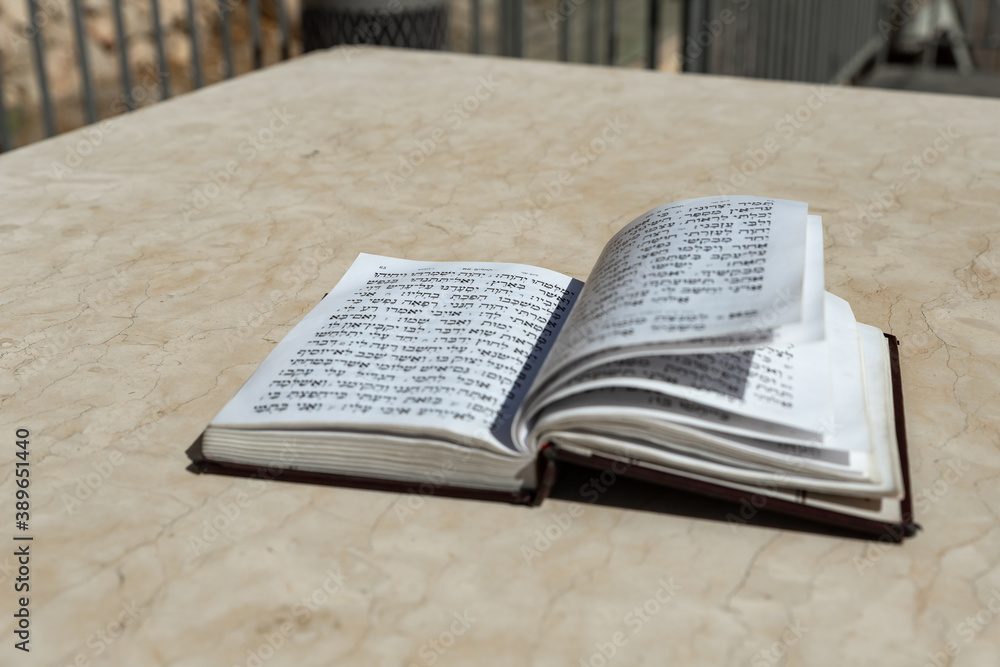Obraz premium The open holy book of Jews with the text of prayers in Hebrew - Tehelim, lies on a table near the Western Wall in the old city. of Jerusalem in Israel
