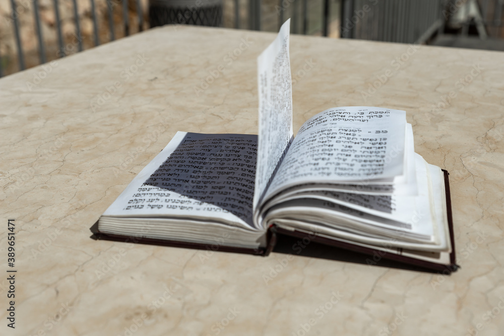 Fototapeta premium The open holy book of Jews with the text of prayers in Hebrew - Tehelim, lies on a table near the Western Wall in the old city. of Jerusalem in Israel