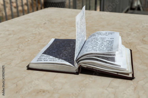 The open  holy book of Jews with the text of prayers in Hebrew - Tehelim, lies on a table near the Western Wall in the old city. of Jerusalem in Israel