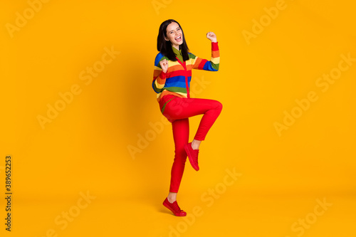 Full body photo of happy smile positive girl celebrate win victory fists hands yell yes isolated over yellow color background
