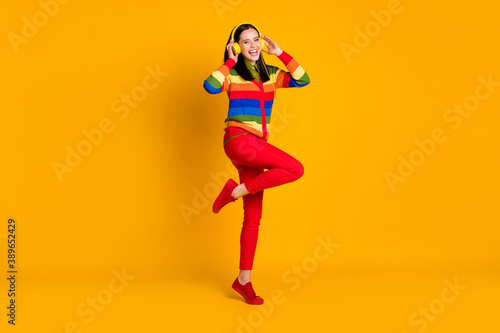 Full body photo of young happy smile woman listen music melody radio hands touch earphones isolated over yellow color background