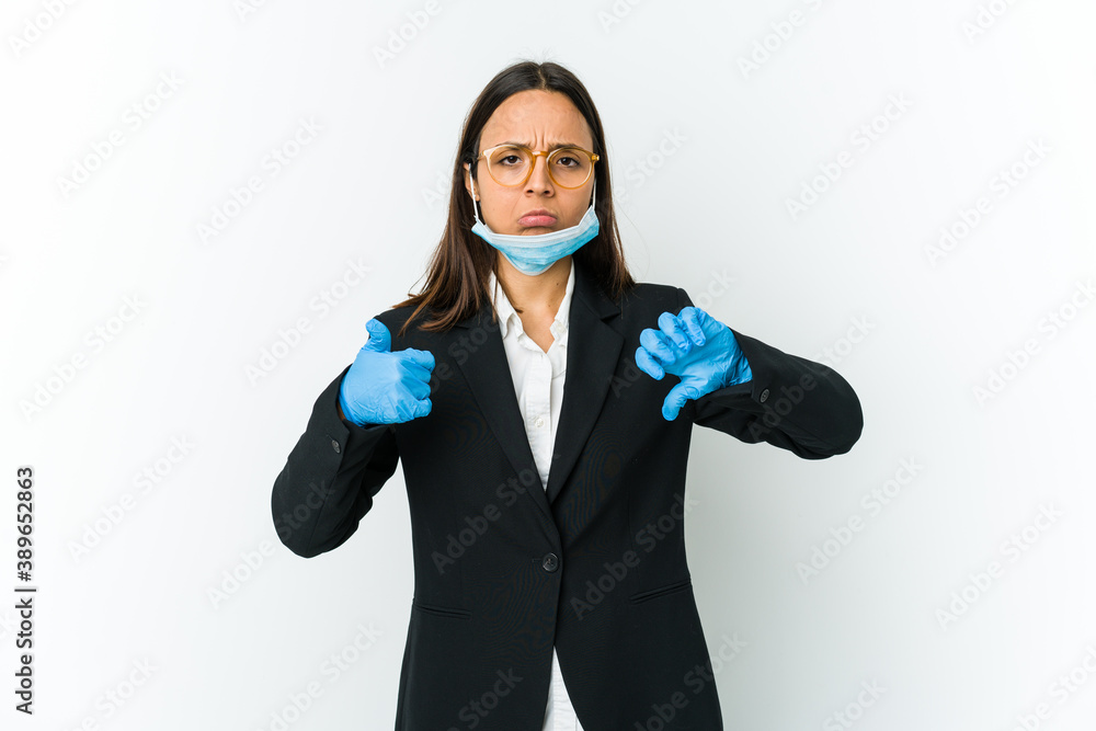 Young business latin woman wearing a mask to protect from covid isolated on white background showing thumbs up and thumbs down, difficult choose concept Young business latin woman wearing a mask to protect from covid isolated on white background showing thumbs up and thumbs down, difficult choose concept