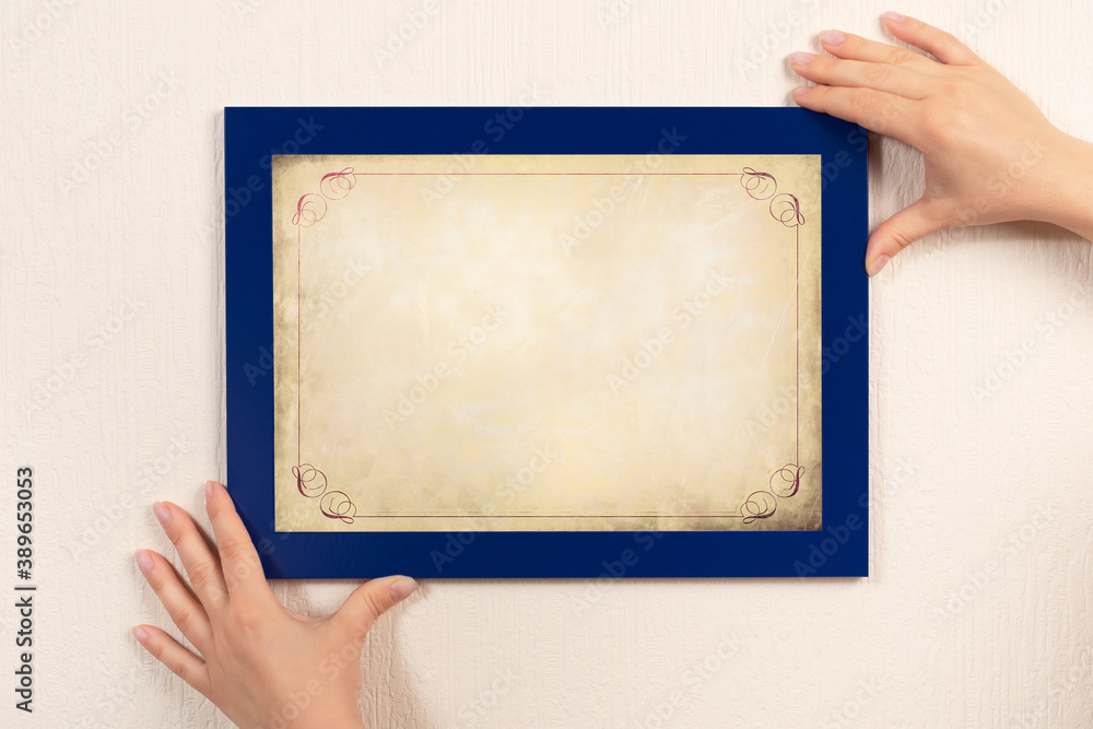 Obraz premium mockup diploma. woman hanging old certificate mockup on wall. White frame mockup