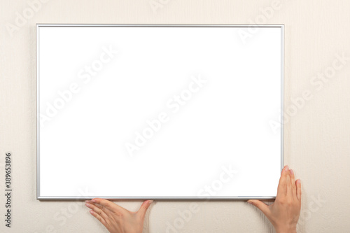 Person hangs a frame on the wall. Empty place for your photo, picture, gratitude letter, design or logo. Horizontal mockup