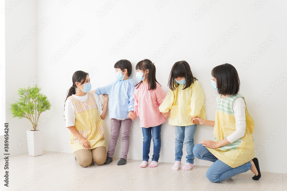 マスクを付けて幼稚園で遊ぶ子どもたちの先生