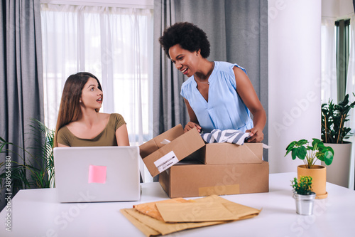 Two young  women helped sell their products online and happily prepared to deliver their products. Selling products online or doing freelance work at home concept. © Mediteraneo